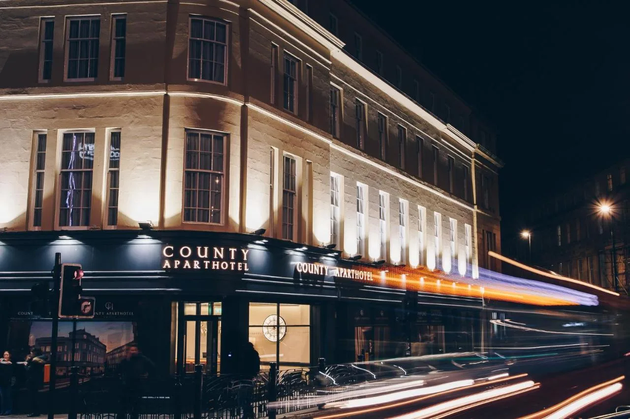 a building on a street with a train passing by at The County Aparthotel in Newcastle upon Tyne